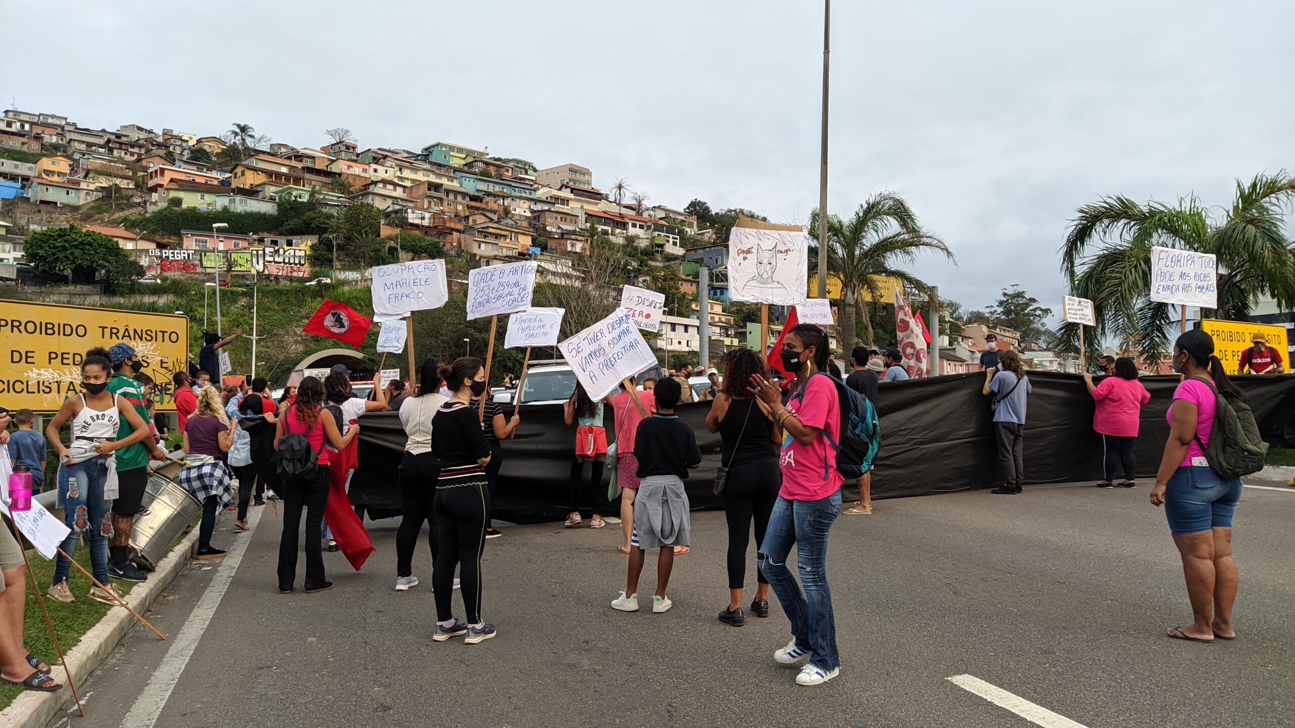 Fotos de manifestantes segurando faixas e cartazes contra despejos sumários em Florianópolis